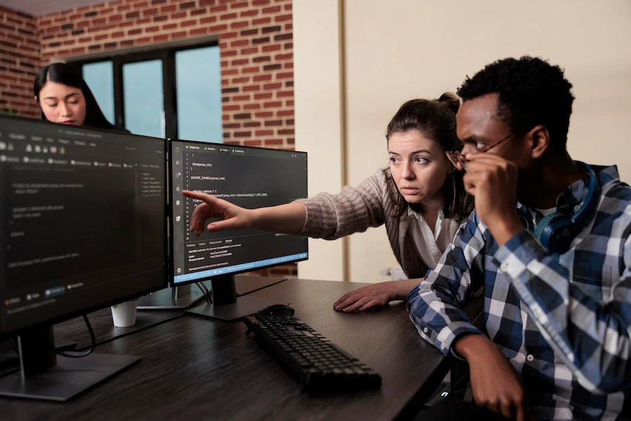 Uma menina e um programador masculino discutindo um código escrito em um computador